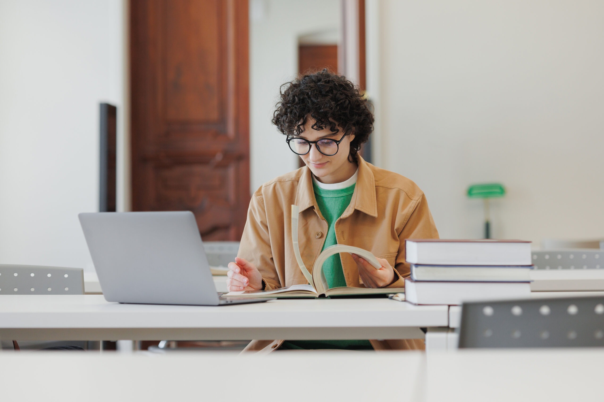 Young woman in a library or coworking works laptop online, education and work creative project, diploma